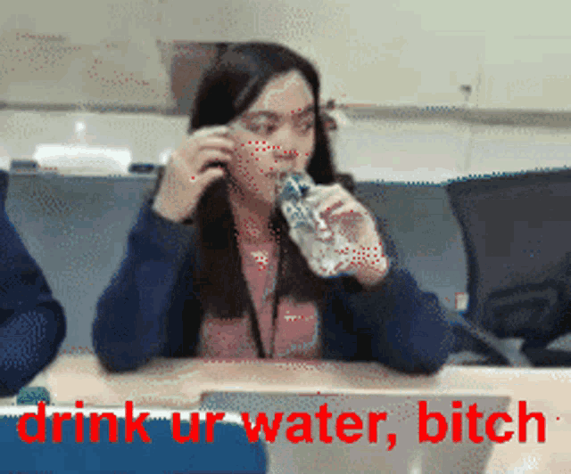 a woman sitting at a desk drinking water with the words drink ur water bitch above her
