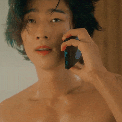 a shirtless man talking on a cell phone with a sticker on it