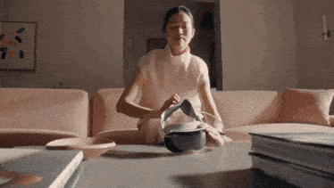 a woman is sitting on a couch holding a remote control