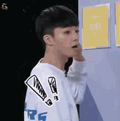 a young boy wearing a white sweater with a drawing of an exclamation point on his sleeve