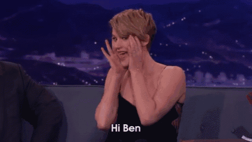 a woman in a black dress with her hands on her face is saying hi ben