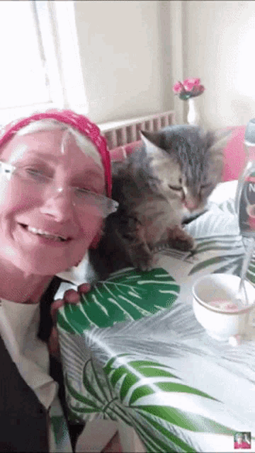 a woman sitting at a table with a cat and a bottle of nescafe on it