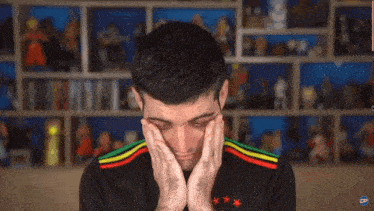 a man is covering his ears with his hands in front of a shelf full of action figures