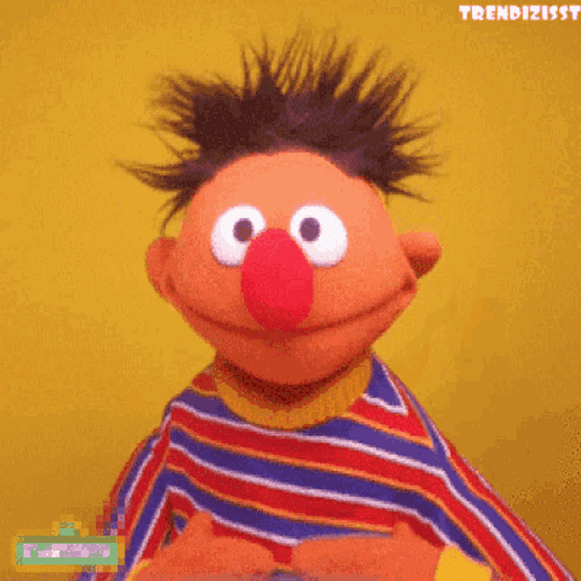ernie from sesame street is smiling and wearing a colorful striped shirt