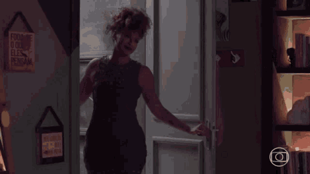a woman standing in front of a door with a sign on the wall that says ' a vida feliz '