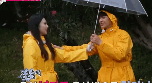 a man in a yellow raincoat holds a clear umbrella over a woman