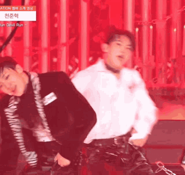a man in a white shirt is dancing with another man in a black suit on a stage .