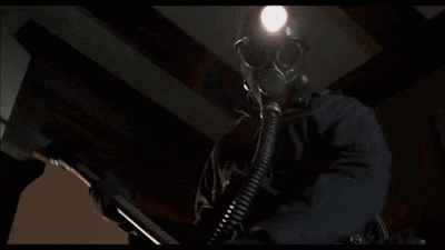 a man wearing a gas mask holds a hammer