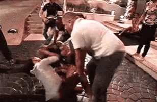 a group of people are standing around a man who is laying on the ground with blood coming out of his mouth .