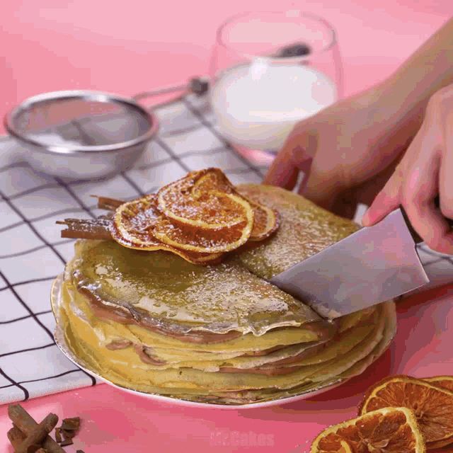 a person is cutting a stack of pancakes on a plate with a knife