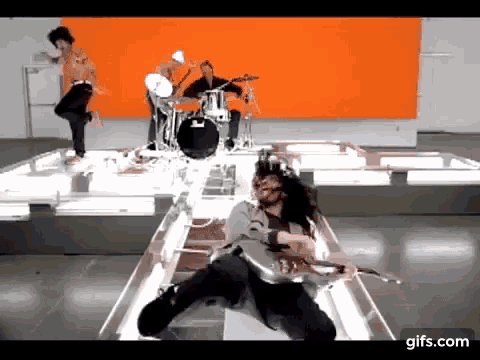 a man is playing a guitar in front of a drum set .
