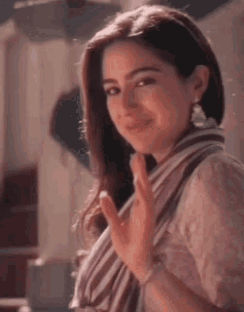 a close up of a woman wearing a scarf and earrings waving her hand .