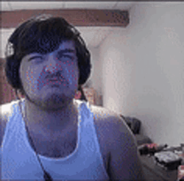 a man wearing headphones and a tank top is making a funny face