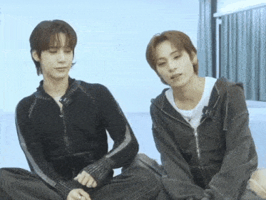 two young men are sitting next to each other and one of them has a ring on his finger