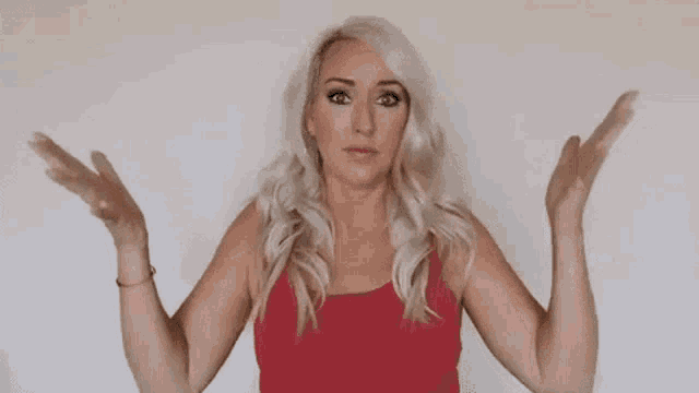 a woman in a red tank top is standing with her arms outstretched .