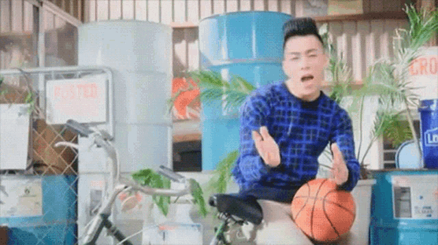 a man sitting on a bicycle holding a basketball in front of a sign that says " played "