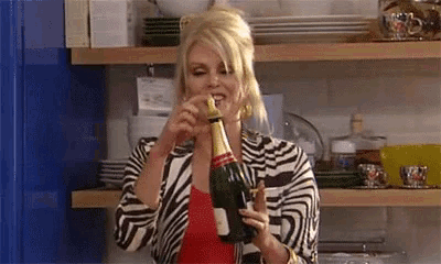 a woman is holding a bottle of champagne in her hand and drinking from it .