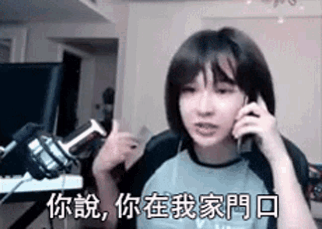 a girl is talking on a cell phone in front of a microphone in a room .