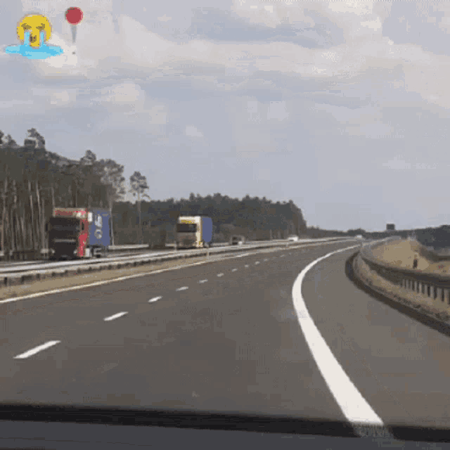 a highway with trucks on it and a balloon with a crying face on it