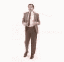 mr bean is dancing with his arms outstretched in a suit and tie .