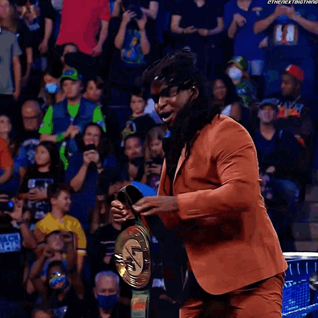 a man in a suit is holding a championship belt