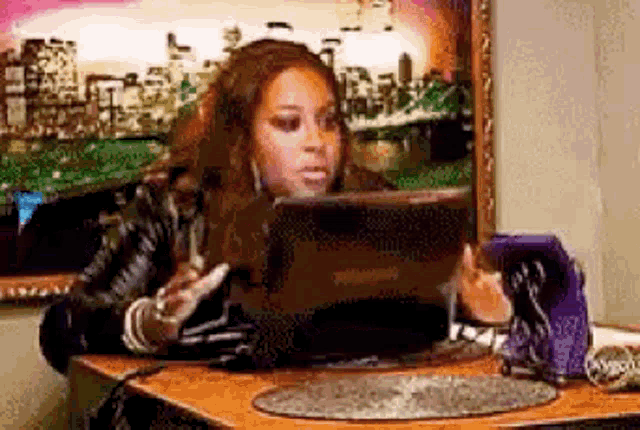 a woman is sitting at a desk using a tablet computer .
