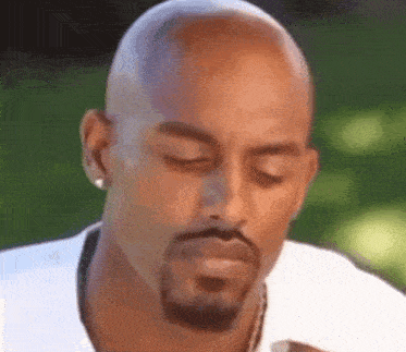 a close up of a bald man with a beard and earrings .