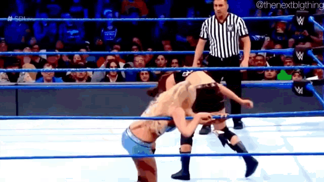 two wrestlers are wrestling in a wrestling ring with a referee watching .