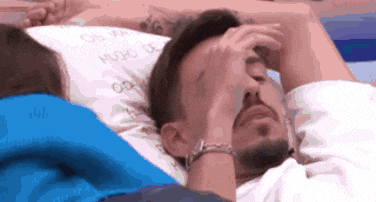 a man with a beard is laying on a pillow that says hugs