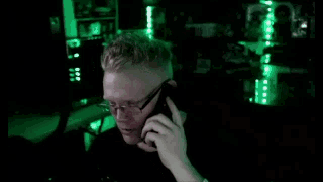 a man wearing glasses talks on a cell phone