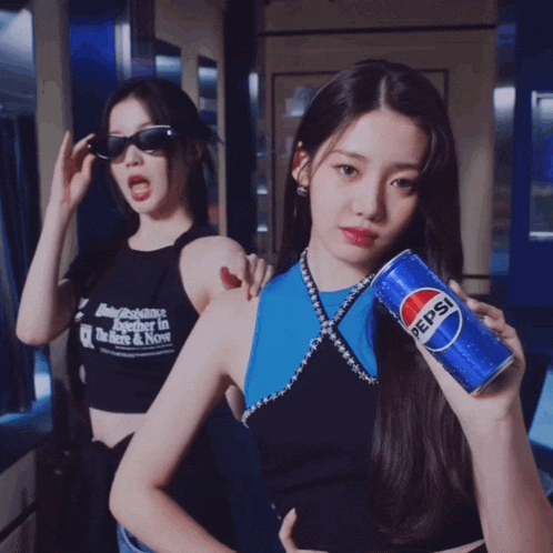 a woman holding a can of pepsi stands next to another woman