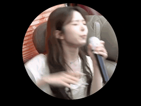 a woman is singing into a microphone while sitting in a chair