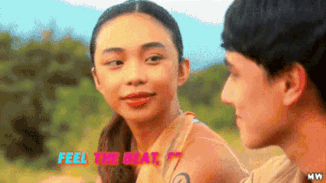 a man and a woman are looking at each other in a field with the words `` feel the beat '' above them .