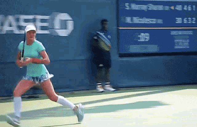 a woman playing tennis in front of a wall that says ase
