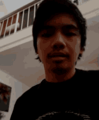 a close up of a man 's face in a dark room with a staircase in the background