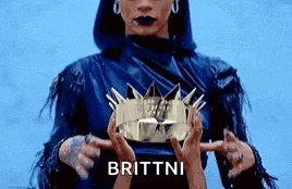 a woman is holding a crown in her hands and pointing at it .