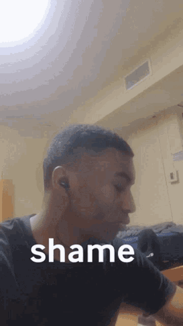 a man is wearing ear buds and the word shame is on the bottom of his face