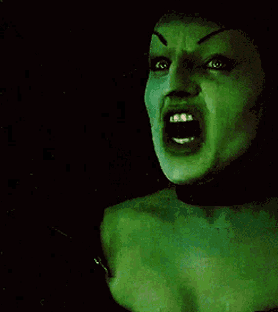 a woman with green face paint is screaming with her mouth wide open