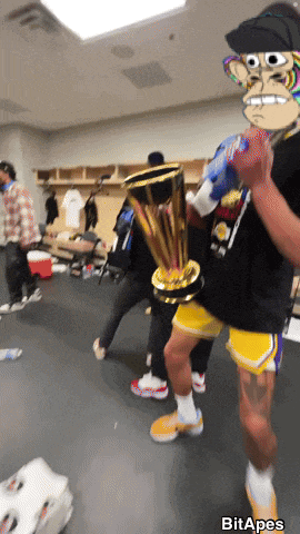 a man holding a trophy in a locker room with a picture of a monkey behind him that says bit apes