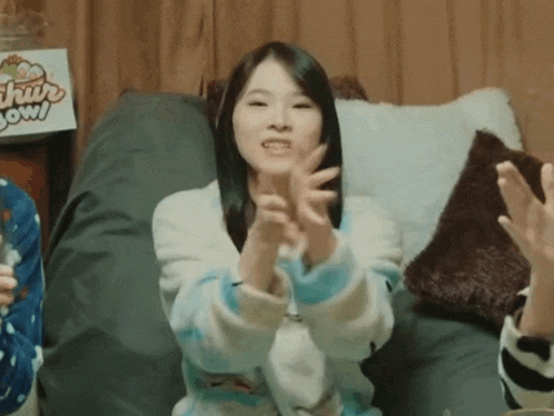a woman is sitting on a bean bag chair clapping her hands