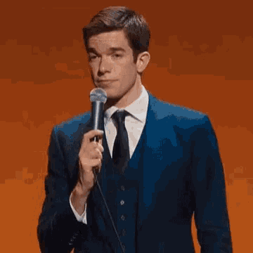 a man in a suit and tie is holding a microphone and speaking into it .