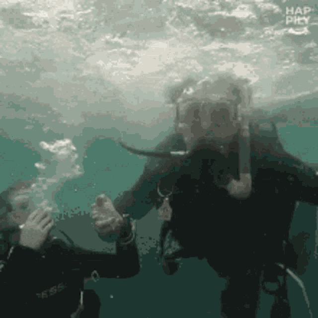 a scuba diver is being helped by another scuba diver in the water ..