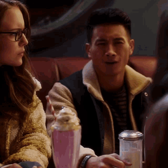 a man and a woman sitting at a table with milkshakes