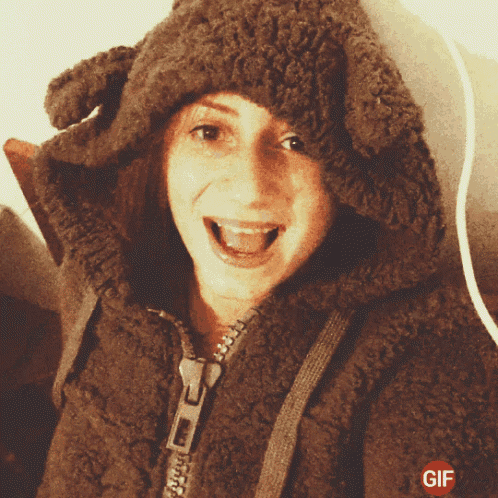 a woman wearing a furry jacket with a zipper and a gif logo on the bottom