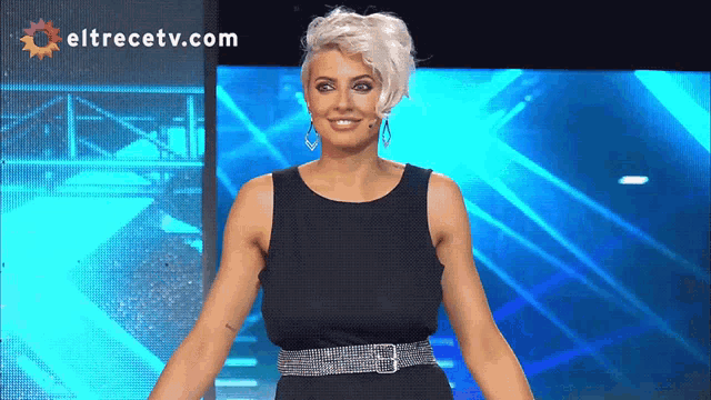 a woman stands in front of a screen with eltrecetv.com on it