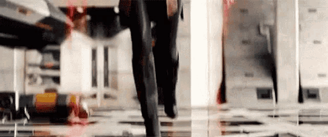 a man in a suit is walking through a room with a red light behind him .