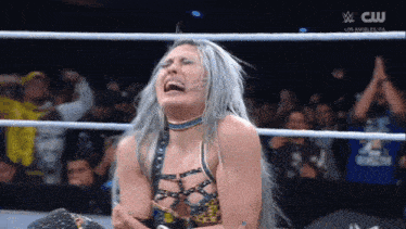 a woman is crying in a wrestling ring with a cw logo on the bottom