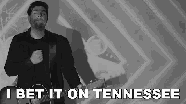 a man holding a guitar with the words i bet it on tennessee
