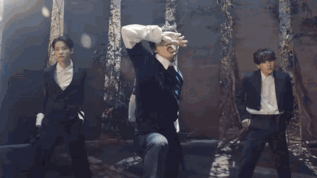 a group of men are dancing in front of trees