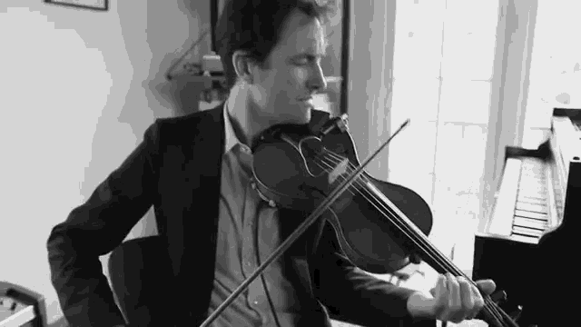 a man in a suit is playing a violin in a black and white photo .